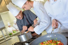 Szef kuchni sprawdza praktykanta ` s niecki jedzenie obrazy stock Szef kuchni sprawdza praktykanta ` s niecki jedzenie obrazy stock