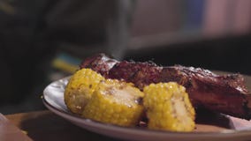 Szef kuchni w czarnych kuchenek rękawiczkach słuzyć na talerzu piec na grillu mięso i pokrajać kawałki piec kukurudza z bliska zbiory Szef kuchni w czarnych kuchenek rękawiczkach słuzyć na talerzu piec na grillu mięso i pokrajać kawałki piec kukurudza z bliska zbiory