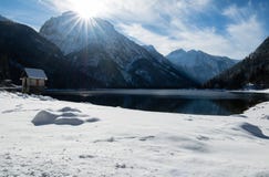 Szenischer Gebirgspass lake Lago Del Predil mit Haus in der Winterlandschaft mit blauem Himmel des Sonnenlichts, Italien Stockbilder Szenischer Gebirgspass lake Lago Del Predil mit Haus in der Winterlandschaft mit blauem Himmel des Sonnenlichts, Italien Stockbilder