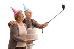 Sêniores felizes com chapéus do partido e um bolo de aniversário que toma um selfi Imagem de Stock Sêniores felizes com chapéus do partido e um bolo de aniversário que toma um selfi Imagem de Stock