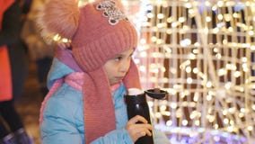 Té De Consumición De La Niña De Un Termo En La Fiesta De Navidad En El Centro De Ciudad Metrajes - Vídeo de niña, ciudad: 153409944
