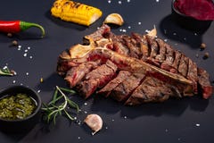 T-bone Porterhouse η μπριζόλα ψήνεται στη σχάρα τεμαχισμένος σε ένα κομμάτι με το ψημένο καλαμπόκι, σάλτσα, τσίλι, δεντρολίβανο, στοκ φωτογραφία με δικαίωμα ελεύθερης χρήσης T-bone Porterhouse η μπριζόλα ψήνεται στη σχάρα τεμαχισμένος σε ένα κομμάτι με το ψημένο καλαμπόκι, σάλτσα, τσίλι, δεντρολίβανο, στοκ φωτογραφία με δικαίωμα ελεύθερης χρήσης