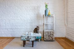 Tabelle, St?hle, Regale auf dem Hintergrund einer wei?en Backsteinmauer im Weinlesedachboden Innen mit Katze stockfotografie Tabelle, St?hle, Regale auf dem Hintergrund einer wei?en Backsteinmauer im Weinlesedachboden Innen mit Katze stockfotografie