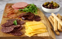 Tabla del aperitivo para el vino o la cerveza con las salchichas, carne secada y queso, servidos con grissini, las hierbas y las fotos de archivo Tabla del aperitivo para el vino o la cerveza con las salchichas, carne secada y queso, servidos con grissini, las hierbas y las fotos de archivo