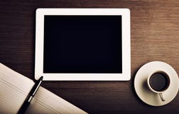 Tablet ПК и кофе и тетрадь с ручкой на столе офиса стоковая фотография Tablet ПК и кофе и тетрадь с ручкой на столе офиса стоковая фотография