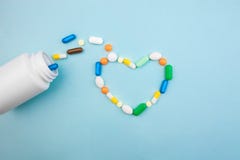 Tabletas multicoloras y cápsulas en forma de corazón, botella blanca para las tabletas, píldoras farmacéuticas de la medicina en fotos de archivo libres de regalías Tabletas multicoloras y cápsulas en forma de corazón, botella blanca para las tabletas, píldoras farmacéuticas de la medicina en fotos de archivo libres de regalías