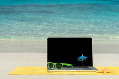 Taccuino del computer sulla spiaggia - fondo di viaggio d'affari immagine stock libera da diritti Taccuino del computer sulla spiaggia - fondo di viaggio d'affari immagine stock libera da diritti