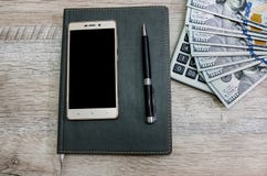 Taccuino, penna, smartphone, calcolatore e dollari su un fondo di legno immagini stock libere da diritti Taccuino, penna, smartphone, calcolatore e dollari su un fondo di legno immagini stock libere da diritti