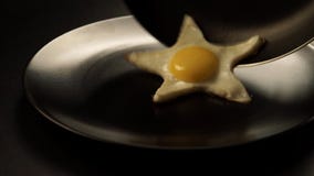Taking out of a fried eggs in a form of a star from the pan to the dish