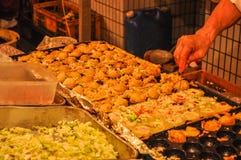 Takoyaki étant fait cuire dans une stalle de nourriture la nuit photographie stock libre de droits Takoyaki étant fait cuire dans une stalle de nourriture la nuit photographie stock libre de droits