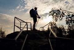 Tall backpacker with poles in hand. Sunny spring daybreak in rocky mountains. Hiker with big backpack, baseball cap, pants and whi royalty free stock images Tall backpacker with poles in hand. Sunny spring daybreak in rocky mountains. Hiker with big backpack, baseball cap, pants and whi royalty free stock images