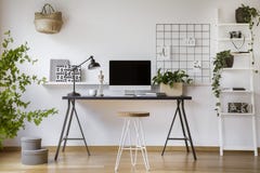 Tamborete do gancho de cabelo que está pela mesa de madeira com tela de computador do modelo, lâmpada do metal e copo de café na fotos de stock Tamborete do gancho de cabelo que está pela mesa de madeira com tela de computador do modelo, lâmpada do metal e copo de café na fotos de stock