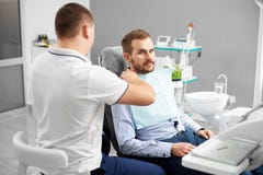 Tandläkaren förbereder patienten för undersökning i den tand- stolen fotografering för bildbyråer Tandläkaren förbereder patienten för undersökning i den tand- stolen fotografering för bildbyråer