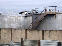 Tanks van de staal schermen de industriële opslag met roestige treden en de gangen achter een sjofel golfijzer en muur stock afbeelding Tanks van de staal schermen de industriële opslag met roestige treden en de gangen achter een sjofel golfijzer en muur stock afbeelding