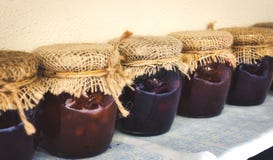 Tarros de cristal de atascos variados cubiertos con harpillera y atados con la secuencia imagen de archivo Tarros de cristal de atascos variados cubiertos con harpillera y atados con la secuencia imagen de archivo