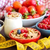 Tarros del yogur, de bayas, del muesli y de la cinta métrica frescos Imagen de archivo libre de regalías Tarros del yogur, de bayas, del muesli y de la cinta métrica frescos Imagen de archivo libre de regalías
