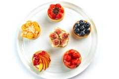 Tartlets com frutos e bagas em uma placa redonda em um fundo branco isolado imagens de stock royalty free Tartlets com frutos e bagas em uma placa redonda em um fundo branco isolado imagens de stock royalty free