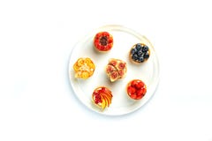 Tartlets com frutos e bagas em uma placa redonda em um fundo branco isolado imagens de stock royalty free Tartlets com frutos e bagas em uma placa redonda em um fundo branco isolado imagens de stock royalty free