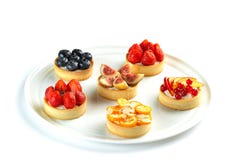 Tartlets com frutos e bagas em uma placa redonda em um fundo branco isolado fotografia de stock Tartlets com frutos e bagas em uma placa redonda em um fundo branco isolado fotografia de stock