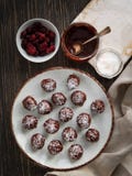 Tartufi di cioccolato sani con i dadi, i datteri, i mirtilli rossi secchi ed i fiocchi della noce di cocco su fondo rustico Vista fotografia stock Tartufi di cioccolato sani con i dadi, i datteri, i mirtilli rossi secchi ed i fiocchi della noce di cocco su fondo rustico Vista fotografia stock