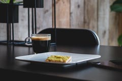 Tasse de café sur une table noire avec un biscuit d'un plat pour le petit déjeuner images stock Tasse de café sur une table noire avec un biscuit d'un plat pour le petit déjeuner images stock