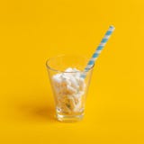 Tasse en verre avec le tube et les guimauves de papier sur un fond jaune Concept de Minimalistic photos stock Tasse en verre avec le tube et les guimauves de papier sur un fond jaune Concept de Minimalistic photos stock
