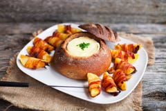 Tasty hot cheese fondue served in a bread roll with potatoes and stock photo Tasty hot cheese fondue served in a bread roll with potatoes and stock photo