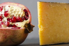 Tasty pomegranate and gouda cheese against grey wall.Closeup view.Fruits and dairy products stock photography Tasty pomegranate and gouda cheese against grey wall.Closeup view.Fruits and dairy products stock photography