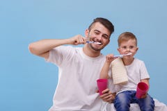 Tata i jego syn szczotkujemy ich zęby na błękitnym tle zdjęcie stock Tata i jego syn szczotkujemy ich zęby na błękitnym tle zdjęcie stock