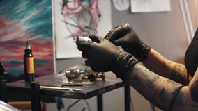 Tatueringkonstnären samlar tatueringmaskinen flickatatueringförlagen förbereder en roterande tatueringmaskingevär för att dra en arkivfilmer Tatueringkonstnären samlar tatueringmaskinen flickatatueringförlagen förbereder en roterande tatueringmaskingevär för att dra en arkivfilmer