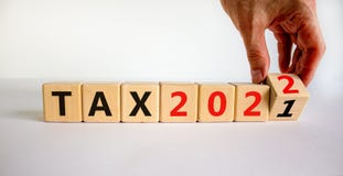 2022 tax new year symbol. Businessman turns wooden cubes and changes words `Tax 2021` to `Tax 2022`. Beautiful white backgroun