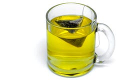 Taza de cristal con la bolsita de té, té verde Aislado en un blanco fotografía de archivo Taza de cristal con la bolsita de té, té verde Aislado en un blanco fotografía de archivo