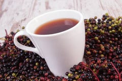 Taza de té caliente con el jugo de la baya del saúco y montón de la baya, nutrición sana Fotos de archivo libres de regalías Taza de té caliente con el jugo de la baya del saúco y montón de la baya, nutrición sana Fotos de archivo libres de regalías