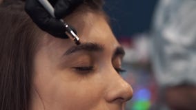 Te?ido de la ceja El amo pinta las cejas con alhe?a a una muchacha hermosa, pinta con un cepillo en el sal?n de a almacen de video Te?ido de la ceja El amo pinta las cejas con alhe?a a una muchacha hermosa, pinta con un cepillo en el sal?n de a almacen de video