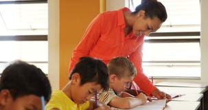 Teacher assisting school kids with their classwork in classroom stock video footage Teacher assisting school kids with their classwork in classroom stock video footage