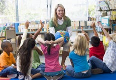 Teacher and children with hands raised in library