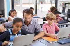 Teacher helping young students using laptops in class royalty free stock image Teacher helping young students using laptops in class royalty free stock image