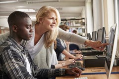 Teacher With Male Student Working On Computer In College Library royalty free stock photography Teacher With Male Student Working On Computer In College Library royalty free stock photography