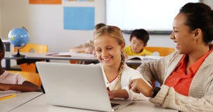 Teacher and schoolgirl using laptop in classroom