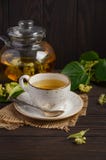Teapot και το φλυτζάνι με το τσάι και τα λουλούδια στο σκοτεινό ξύλινο πίνακα Στοκ Φωτογραφίες Teapot και το φλυτζάνι με το τσάι και τα λουλούδια στο σκοτεινό ξύλινο πίνακα Στοκ Φωτογραφίες