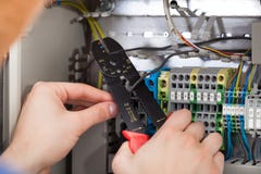 Technician cutting cable with fusebox in background royalty free stock image Technician cutting cable with fusebox in background royalty free stock image