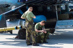 Technicians inspect attack helicopter with transport capabilities Mil Mi-24 Hind. stock image Technicians inspect attack helicopter with transport capabilities Mil Mi-24 Hind. stock image