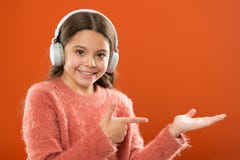 Technologie moderne sans fil d'écouteurs L'enfant de fille écoutent les écouteurs sans fil de musique se dirigeant avec l'index O images stock Technologie moderne sans fil d'écouteurs L'enfant de fille écoutent les écouteurs sans fil de musique se dirigeant avec l'index O images stock
