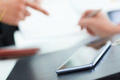 Technologies make life easier. Business persons sign a contract while mobile phone laying on foreground. Royalty Free Stock Photo Technologies make life easier. Business persons sign a contract while mobile phone laying on foreground. Royalty Free Stock Photo