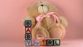 Teddy bear falling onto baby blocks and pink soother