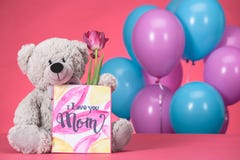teddy bear with pink tulip and postcard with text I Love You Mom, mothers