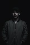 teen boy posing with black cap and bomber jacket in front of black background stock photo teen boy posing with black cap and bomber jacket in front of black background stock photo