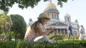 Teen girl tourist sitting searching information on a smart phone on vacations on the city street. Technology, leisure stock video Teen girl tourist sitting searching information on a smart phone on vacations on the city street. Technology, leisure stock video