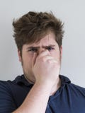 Teenage boy in dark blue shirt holding his nose to demonstrate bad smell stock images Teenage boy in dark blue shirt holding his nose to demonstrate bad smell stock images