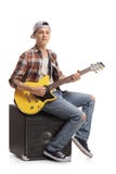 Teenage boy with an electric guitar sitting on an amplifier Royalty Free Stock Images Teenage boy with an electric guitar sitting on an amplifier Royalty Free Stock Images